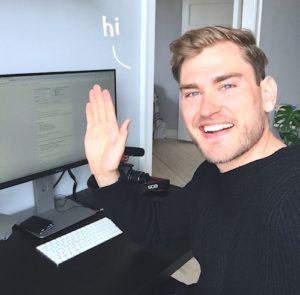 Photo of Rued sitting at his computer and waving